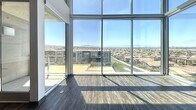 This sophisticated multi-level residence in Henderson, NV spans 2,170 square feet across three floors, each thoughtfully designed with modern finishes and an open, airy aesthetic. The ground floor (670 sq ft) provides an accessible entry point, while the main living level (760 sq ft) showcases a chef-inspired kitchen featuring a large center island with a gas cooktop and stainless steel hood vent, sleek light wood cabinetry, white quartz countertops, stainless steel appliances including a double wall oven, built-in microwave, dishwasher, and French door refrigerator, complemented by dark hardwood flooring. The bathrooms are elegantly appointed with wood cabinetry, vessel sinks, stone countertops, large-format tile flooring, and walk-in tile showers. Bedrooms offer plush carpeting and sliding glass doors opening to private balconies with sweeping views of the Henderson cityscape and surrounding mountains. The top floor (740 sq ft) is a standout highlight, featuring floor-to-ceiling glass walls and a glass-railed open staircase that frames breathtaking panoramic views of the Nevada landscape. Recessed lighting, dark baseboards, and clean neutral walls unify the space with a polished, contemporary character throughout.