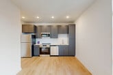 Located at 9420 Grand Blvd in Upper Marlboro, MD, this well-appointed 2-bedroom, 2-bathroom residence offers a thoughtfully designed single-floor layout that maximizes every inch of space. Light-toned luxury vinyl plank flooring flows seamlessly throughout, complementing the clean, modern aesthetic defined by crisp white walls and bright recessed lighting.

The open-concept living, dining, and kitchen area serves as the heart of the home. The kitchen is a standout feature, boasting slate-gray shaker-style cabinetry, white quartz countertops, a classic subway tile backsplash, and a full suite of stainless steel appliances including a refrigerator, range, built-in microwave, and dishwasher — ideal for both everyday cooking and entertaining.

Both bedrooms are well-proportioned and bathed in natural light, with the primary bedroom offering generous closet space. The two bathrooms mirror each other in design, each featuring subway-tiled tub-and-shower combinations, gray vanities with quartz countertops, and large mirrors with modern chrome fixtures. Additional highlights include six closets providing ample storage, a dedicated laundry area, and a central hallway connecting all rooms with ease. The overall ambiance is clean, contemporary, and move-in ready.