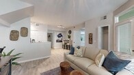 This single-story, 3-bedroom, 2-bathroom home is thoughtfully designed to maximize its compact footprint. Light-toned luxury vinyl plank flooring flows throughout, complementing the neutral gray-and-white color palette that lends the space a clean, cohesive aesthetic.

The living room serves as the heart of the home, featuring large windows that invite abundant natural light, a ceiling fan, and an open layout that connects seamlessly to a dining area. Track lighting overhead adds functional illumination. A partially open partition separates the living space from the kitchen, which features white cabinetry, light stone countertops, and white appliances including a refrigerator, stove, dishwasher, and microwave.

The primary bedroom offers a comfortable retreat with hardwood-style flooring and ample space. A second bedroom includes a closet with bifold doors. Both full bathrooms are finished with white vanities, stone countertops, and tub-shower combinations.

The attached garage provides generous utility space, housing washer and dryer units alongside room for additional storage. A hallway connects the bedrooms and bathrooms, completing the efficient, well-organized floor plan.