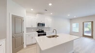 This two-story home in Augusta, Georgia offers a thoughtfully designed layout spread across two floors. The main level features an open-concept kitchen and living area anchored by a large center island with quartz countertops and an undermount sink. White shaker cabinetry, a subway tile backsplash, and stainless steel appliances—including a range, built-in microwave, dishwasher, and refrigerator—give the kitchen a clean, modern aesthetic. Light hardwood-style flooring flows throughout the main level, complementing the neutral color palette. The living room is bright and airy, with multiple windows that invite natural light and provide outdoor views, along with a ceiling fan for added comfort. A hallway connects to the attached garage and a convenient half bath on the main floor. Upstairs, two generously sized bedrooms each feature ceiling fans and hardwood-style flooring. The primary bedroom includes an en suite bathroom with a walk-in glass-door shower. Three additional closets provide ample storage throughout. A dedicated laundry room on the upper level houses a full-size washer and dryer. The attached garage offers secure parking and additional storage. The home's bright, neutral finishes and functional floor plan create a comfortable and move-in-ready living environment.