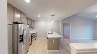 This thoughtfully designed single-floor residence combines modern finishes with a functional layout throughout. Light hardwood flooring runs consistently across the living areas and bedrooms, creating a cohesive and airy feel. The open kitchen serves as a central hub, featuring taupe shaker-style cabinetry with brushed hardware, light quartz countertops, and a full suite of stainless steel appliances including a refrigerator, electric range, and built-in microwave. A center island with a undermount sink and elegant pendant lighting above adds both workspace and visual appeal.

The living area is bathed in natural light from sliding glass doors that open to a private balcony, offering outdoor views of the surrounding neighborhood. Vaulted ceilings with a ceiling fan enhance the sense of volume in the bedrooms, each of which features bright windows and generous proportions.

The bathroom is finished with marble-style tile surrounding a full soaking tub and shower combination, complemented by a clean vanity with ample counter space and a large mirror. A dedicated utility closet houses a stacked Whirlpool washer and dryer, while a separate mechanical closet contains a Carrier HVAC system, ensuring year-round comfort.