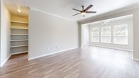 Located in Allen, TX, this single-story 2-bedroom, 2-bathroom home offers a well-designed layout with a comfortable, functional flow throughout. The living room is a standout space, featuring wood-look flooring, crown molding, a classic white-mantled fireplace, and a ceiling fan. Large windows flood the room with natural light and offer views of the surrounding greenery. The kitchen is outfitted with white cabinetry, light countertops, stainless steel appliances including a refrigerator, dishwasher, and range, and a peninsula that connects conveniently to the living area. Wood-look flooring continues throughout the main areas, creating a cohesive aesthetic. Both bedrooms are carpeted and feature ceiling fans and windows with outdoor views. The primary bedroom is a generous size and includes a walk-in closet with wire shelving on multiple walls for ample storage. The bathrooms include a tub-shower combination with tiled surround accented by decorative diamond-pattern tiles. A dedicated laundry area houses a full-size washer and dryer. Two closets provide additional storage throughout the home, rounding out this practical and inviting residence in Allen, TX.