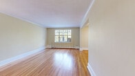 This single-floor residence offers a well-organized layout comprising two bedrooms, two bathrooms, a living room, kitchen, two hallways, and two closets. Classic architectural details are present throughout, including crisp crown molding and generous baseboards that lend a timeless character to the space.

The living area is a standout feature, showcasing gleaming hardwood floors that extend through the hallways and main living spaces. Natural light fills the room through large multi-pane windows, complemented by a ceiling fan and a baseboard heating system. The space flows openly into an adjoining area, providing a generous and connected feel.

The kitchen is outfitted with white cabinetry, dark laminate countertops, a stainless steel sink, and a white electric range. A window above the sink allows natural light to brighten the workspace, which features tile flooring throughout.

Both bedrooms are carpeted and accented with crown molding. The primary bedroom includes a ceiling fan, while each bedroom benefits from dedicated closet space fitted with hanging rods. The bathrooms feature a tub-shower combination with distinctive sage green square tile surround and chrome fixtures, adding a classic touch to the overall design.