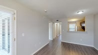 This single-floor residence offers a thoughtfully designed layout with a clean, neutral aesthetic throughout. The main living area features durable hardwood-style flooring and a textured ceiling, with natural light streaming in through a large window fitted with blinds. A sliding glass door opens to a private balcony, extending the living space outdoors and offering greenery views.

The kitchen is a standout feature, equipped with rich dark espresso cabinetry, light granite countertops, a stainless steel refrigerator, and a stainless steel sink — combining both style and practicality. The kitchen connects seamlessly to the main living and hallway areas.

A central hallway links the primary rooms, with louvered closet doors visible along the corridor, providing ample storage throughout. The bedrooms are carpeted for comfort and include ceiling fans with light fixtures. The primary bedroom features dual reach-in closets with built-in rods and a window for natural light, while a second carpeted bedroom also includes a ceiling fan and window with exterior views.

The bathroom includes a full tub and shower combination with white subway-style tile surround and chrome fixtures, maintaining a clean and classic look. Central HVAC with ceiling vents ensures climate control throughout. Overall, the space presents a functional and inviting environment with consistent finishes across all rooms.