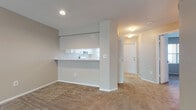 Located at 7501 Ulmerton Rd in Largo, Florida, this single-floor unit offers a practical and comfortable layout designed for everyday living. The spacious living room is a standout feature, highlighted by a graceful arched alcove framing a large window dressed with vertical blinds, filling the room with natural light. A ceiling fan overhead and soft wall-to-wall carpeting throughout the living areas add to the relaxed ambiance.

The kitchen is efficiently designed with white cabinetry, light speckled countertops, a stainless steel sink, and a coil-burner electric range. A pass-through counter opens directly to the living area, creating a connected, open feel ideal for entertaining or casual dining.

The unit includes two bathrooms, each featuring wood-look vinyl plank flooring, white vanities with light countertops, and tub/shower combinations with white tile surrounds. One bathroom also includes a walk-in shower configuration, offering added flexibility.

A dedicated in-unit laundry area houses a full-size GE top-load washer and dryer, providing added convenience. The bedrooms are carpeted and receive natural light through windows with vertical blinds. A textured ceiling and neutral wall tones are consistent throughout, lending the space a clean, cohesive aesthetic well-suited for a variety of furnishing styles.