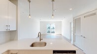 Located along US-9 North in Howell, NJ, this well-appointed one-bedroom, one-bathroom unit is part of a contemporary multi-story residential building with classic architectural detailing, including pitched rooflines and private balconies. The interior features light wood-tone flooring throughout, crisp white walls, and an abundance of natural light, creating a clean and modern aesthetic.

The open-concept kitchen is outfitted with white cabinetry, white quartz countertops, a subway tile backsplash, and a full suite of stainless steel appliances, including a refrigerator with ice maker, range, and built-in microwave. A kitchen island with an undermount sink and brushed gold pendant lighting anchors the space and connects seamlessly to the living area.

The living room is bright and airy, benefiting from large sliding glass doors that open to a private balcony with outdoor views of the surrounding greenery and neighborhood. The spacious primary bedroom also features a sliding glass door to a balcony, along with additional windows that allow natural light to pour in from multiple angles. A dedicated closet provides practical storage.

The bathroom is finished in a modern style with light tile flooring, a white floating vanity with quartz countertops, brushed gold hardware, a large mirror, and a separate soaking tub and shower area.