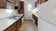 Located at 2356 N Limestone St in Springfield, Ohio, this single-floor unit offers a practical and functional layout designed for comfortable everyday living. The galley-style kitchen is efficiently organized, featuring dark wood cabinetry on both sides, white laminate countertops, a stainless steel sink, and white appliances including a range, dishwasher, and refrigerator. Wood-look vinyl flooring and a window providing natural light complete the kitchen's clean, utilitarian character.

The living area is generously proportioned, with neutral-toned carpet and a sliding glass door fitted with vertical blinds that opens to an outdoor view, allowing natural light to fill the space. The open sightline to the kitchen creates a connected, flowing feel between the two areas.

The bedrooms are carpeted and offer a comfortable sense of space. Each features mirrored sliding closet doors, providing both storage and a visually expansive quality. One bedroom includes a ceiling fan with a wood-accented fixture. Neutral wall tones carry throughout all rooms, contributing to a calm, cohesive ambiance.

The bathroom is finished with white square wall tiles surrounding the tub-shower combination, wood-look flooring, a white vanity, and a wall-mounted mirror, presenting a clean and bright aesthetic throughout.