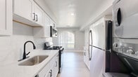 Located at 722 Clopper Rd in Gaithersburg, MD, this single-floor home offers three bedrooms, two bathrooms, and a thoughtfully designed layout that maximizes comfort and functionality. The interior is finished with a clean, modern aesthetic, featuring crisp white walls, neutral-toned carpet in the living and bedroom areas, and light hardwood-style flooring in the kitchen.

The galley-style kitchen is a standout feature, showcasing white shaker cabinets with matte black hardware, quartz countertops, a white subway tile backsplash, and stainless steel appliances including a gas range, built-in microwave, dishwasher, and refrigerator. A window at the end of the kitchen allows natural light to flow through the space.

The generously sized primary bedroom offers ample room to move, with a bright window dressed in vertical blinds and views of surrounding greenery. Additional bedrooms are well-proportioned and share the same carpeted, light-filled character. Closets are equipped with wire shelving systems for organized storage.

Both bathrooms are finished with large-format tile in a neutral gray tone. One features a tub-shower combination, while the other includes a walk-in shower with matte black fixtures. The living area connects fluidly to the kitchen, creating an open and airy feel throughout this well-appointed home.