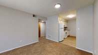 Located at 792 Inland Cir in Naperville, IL, this single-floor unit offers a practical and straightforward layout designed for comfortable everyday living. The living area is finished with neutral-toned carpet and painted in soft gray tones, creating a clean and understated aesthetic throughout. A sliding glass door with vertical blinds allows natural light to fill the space while providing access to the outdoors.

The galley-style kitchen is efficiently organized, featuring white cabinetry on both sides, laminate wood-look flooring, and white appliances including a refrigerator, electric range, and dishwasher. A double sink with a speckled countertop completes the functional workspace. The kitchen opens toward a utility area and a back door, adding convenience to daily routines.

The bedrooms are carpeted and finished in neutral tones, each featuring windows with blinds that bring in natural light. The rooms offer ample wall space suitable for flexible furniture arrangements.

The bathroom includes a white vanity with a speckled countertop, a large mirror, and a full soaking tub with a shower surround, all set on wood-look flooring. The entry area transitions between the kitchen and living space, completing this well-organized, single-level layout.