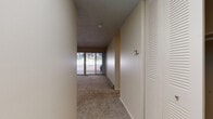 This single-floor residence is thoughtfully laid out to maximize functionality across its living spaces. The entry opens into a carpeted hallway, with a louvered closet door providing convenient storage near the front entrance. A thermostat is positioned along the wall, reflecting practical accessibility throughout the unit.

The living area is generously proportioned, featuring plush carpeting, a textured ceiling, and a baseboard heating system along the perimeter walls. A full wall of sliding glass doors floods the space with natural light and provides direct access to an outdoor patio area, offering views of a distinctive natural rock formation that serves as a scenic backdrop.

The bedroom is a quiet, carpeted room with a window framing the same rocky outdoor landscape, contributing a sense of natural surroundings to the interior.

The galley-style kitchen is well-appointed with rich dark cabinetry, white quartz countertops, warm hardwood flooring, and a full suite of stainless steel appliances including a refrigerator, range, and microwave. A single-basin sink with a modern faucet completes the functional workspace.

The bathroom features a full tub-shower combination with tile surround, complemented by dark vanity cabinetry consistent with the kitchen's design aesthetic.