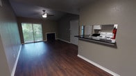 This single-floor, 2-bedroom, 1-bathroom residence offers a practical and cohesive layout throughout. Rich, dark hardwood-style flooring runs continuously across all rooms, providing a unified and polished look. The open-concept living and dining area is a central highlight, featuring a ceiling fan, a wood-burning fireplace, and a sliding glass door that lets in natural light and provides access to an outdoor area with views of surrounding greenery. The kitchen is designed in a galley style, equipped with white cabinetry, dark granite countertops, a white electric range, a refrigerator, and a stainless steel sink. A pass-through counter opens the kitchen to the living space, enhancing the sense of openness. Both bedrooms are generously proportioned, each featuring ceiling fans and neutral gray walls. One bedroom benefits from a window with natural views of mature trees, while the other includes access to additional closet space. The bathroom is clean and functional, featuring a full-size soaking tub with a tiled shower surround and brushed nickel fixtures. Throughout the residence, white baseboards provide a crisp contrast to the gray walls and dark flooring, creating a cohesive, modern aesthetic.