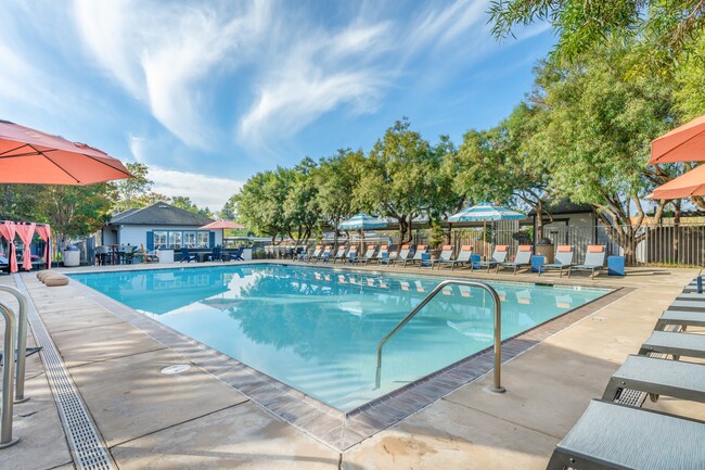 La piscina estilo resort está llena de tumbonas y sombrillas - Harvest Park Apartment Homes