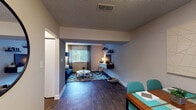 This single-floor residence offers a thoughtfully designed layout across several distinct living areas. The open living room serves as the centerpiece of the home, featuring dark hardwood-style flooring, gray-toned walls, and a floating media wall with shelving. A large window fitted with blinds and draping curtains allows natural light to filter in, illuminating the space and enhancing its modern, comfortable ambiance.

The kitchen is well-equipped and functional, showcasing rich dark cabinetry with brushed silver hardware, white countertops, black appliances, and a window above the sink that brings in additional natural light. A dedicated laundry closet provides in-unit washer and dryer hookups for added convenience.

The primary bedroom is a calming retreat, dressed in soft blue-gray tones with plush carpeting, a window with patterned curtains, and a textured ceiling. A second bedroom offers a neutral palette with warm beige walls, carpeted flooring, and a window that allows natural light to brighten the room.

The bathroom features wood-look tile flooring, a dark vanity with a white countertop sink, a well-lit mirror, and a shower-tub combination. Throughout the residence, consistent use of wood-style flooring, textured ceilings, and a cohesive color scheme create a unified and inviting atmosphere.