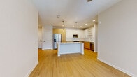 Located in Longwood, FL, this well-appointed 2-bedroom, 2-bathroom residence offers a thoughtfully designed single-floor layout. The open-concept living area seamlessly connects the kitchen, dining, and living spaces, all finished with light-toned hardwood-style flooring that enhances the bright, airy atmosphere. The kitchen is a standout feature, boasting a large center island with a crisp white countertop, two-tone cabinetry pairing white uppers with warm natural wood lowers, stainless steel appliances, a subway tile backsplash, open shelving, and pendant lighting. A ceiling fan and large windows in the living area invite natural light, while a private balcony offers views of the resort-style pool and courtyard below. The primary bedroom is generously sized with plush carpeting and is accompanied by a spacious walk-in closet with wire shelving. The second bedroom also features carpet flooring and large windows with blinds. Both bathrooms include light wood vanities and hardwood-style flooring. Additional conveniences include an in-unit laundry area, a pantry, and four closets providing ample storage throughout.
