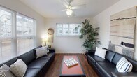 This three-floor residence is designed with functionality and comfort in mind, offering a well-organized layout across its levels. The living area features rich hardwood-style flooring, white walls, and ceiling fans that promote airflow throughout. Natural light filters in through blinds-fitted windows, creating a bright and welcoming atmosphere. The space accommodates ample seating and opens via a glass-paneled door to an outdoor area, enhancing connectivity between interior and exterior spaces.

The kitchen is equipped with light wood cabinetry, a double sink, a dishwasher, a range with an overhead microwave, and generous counter space. A window above the sink allows natural light to brighten the workspace.

Each bedroom is carpeted and features a ceiling fan, windows with blinds, and a dedicated desk area—providing a practical setup conducive to both rest and study. Bathroom facilities are clean and functional, with vanity sinks, large mirrors, tiled flooring, and natural light from windows.

Overall, the space maintains a consistent neutral palette with white walls and warm wood-tone flooring throughout common areas, offering a cohesive and livable environment.