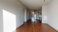 Located at 380 W 13th Ave in Denver, CO, this single-floor residence offers a contemporary design with a cohesive, modern aesthetic throughout. The open-concept layout connects the living area to the kitchen, creating a spacious, functional flow anchored by rich hardwood-style flooring that extends through the main living spaces.

The kitchen is a standout feature, showcasing light gray flat-front cabinetry, a white subway tile backsplash, and a granite-topped island with a curved edge that provides additional prep and seating space. Stainless steel appliances—including a refrigerator, electric range, microwave, and dishwasher—complement the contemporary design, while pendant lighting and a track light fixture add warmth and task illumination overhead.

The bedroom is generously sized with soft carpeting underfoot and a large window that invites abundant natural light and offers views of the surrounding Denver skyline and neighboring architecture. The bright, airy atmosphere makes this room a comfortable retreat.

The bathroom continues the modern design language with granite countertops, gray cabinetry with brushed hardware, a soaking tub with white subway tile surround, and hardwood-style flooring. An adjacent walk-in closet with built-in shelving provides practical storage. The unit also includes an in-unit washer and dryer, adding everyday convenience.