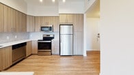 Located at 19279 NW 27th Ave in Miami Gardens, Florida, this 1-bedroom, 1-bathroom residence offers a thoughtfully designed single-floor layout with a clean, contemporary aesthetic throughout. Wood-look flooring runs continuously across the main living areas, lending warmth and visual cohesion to the space.

The open-concept kitchen is a standout feature, outfitted with two-tone wood grain cabinetry extending to the ceiling for ample storage, a marble-style tile backsplash, white quartz countertops, a black undermount sink, and a full suite of stainless steel appliances including a refrigerator, electric range, microwave, and dishwasher. A breakfast bar with pendant lighting connects the kitchen to the living area, creating a natural flow ideal for everyday living and entertaining.

The living area is bright and open, benefiting from natural light and direct access to a private balcony through sliding glass doors, offering views of the surrounding community and greenery. The bedroom is well-proportioned, featuring a large window with outdoor views and light-filtering roller shades.

The bathroom presents a modern finish with wood grain vanity cabinetry, white quartz countertops, a large mirror, light tile flooring, and contemporary light fixtures. The overall ambiance of the residence is fresh, modern, and move-in ready.