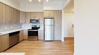 Located at 19279 NW 27th Ave in Miami Gardens, Florida, this 1-bedroom, 1-bathroom residence offers a thoughtfully designed single-floor layout with a clean, contemporary aesthetic throughout. Wood-look flooring runs continuously across the main living areas, lending warmth and visual cohesion to the space.

The open-concept kitchen is a standout feature, outfitted with two-tone wood grain cabinetry extending to the ceiling for ample storage, a marble-style tile backsplash, white quartz countertops, a black undermount sink, and a full suite of stainless steel appliances including a refrigerator, electric range, microwave, and dishwasher. A breakfast bar with pendant lighting connects the kitchen to the living area, creating a natural flow ideal for everyday living and entertaining.

The living area is bright and open, benefiting from natural light and direct access to a private balcony through sliding glass doors, offering views of the surrounding community and greenery. The bedroom is well-proportioned, featuring a large window with outdoor views and light-filtering roller shades.

The bathroom presents a modern finish with wood grain vanity cabinetry, white quartz countertops, a large mirror, light tile flooring, and contemporary light fixtures. The overall ambiance of the residence is fresh, modern, and move-in ready.