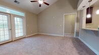 Located at 9501 Washington Cir in Fredericksburg, Virginia, this single-floor residence offers a well-designed layout with a blend of comfort and modern finishes throughout. The living area is a standout feature, boasting soaring vaulted ceilings with a ceiling fan and soft carpeting underfoot. An open pass-through connects the living space directly to the kitchen, which is appointed with dark cabinetry, granite countertops, stainless steel appliances including a full-size refrigerator and dishwasher, and warm wood-look flooring. The bedrooms are generously sized, each with plush carpet and windows that bring in natural light and outdoor views. Multiple walk-in closets provide abundant storage, each outfitted with multi-tier wire shelving systems. The bathrooms feature granite-topped vanities with dark cabinetry, wood-look vinyl flooring, and tub-shower combinations, maintaining a consistent and cohesive aesthetic throughout the home. Neutral warm-toned walls and crisp white trim are carried throughout every room, creating a clean and inviting ambiance. The overall design emphasizes functionality and practicality, making this a well-appointed single-level home in the Fredericksburg area.