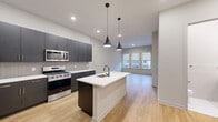 This well-appointed residence at 51 Okner Pkwy in Livingston, NJ offers a thoughtfully designed single-floor layout with 1 bedroom, 2 bathrooms, a den, and generous storage throughout. Light-toned hardwood flooring flows consistently across the entire space, creating a cohesive and inviting aesthetic.

The open-concept kitchen and living area serves as the heart of the home. The kitchen is outfitted with dark navy cabinetry, stainless steel appliances including a gas range, microwave, and French door refrigerator, a subway tile backsplash, and a central island with a white quartz countertop, undermount sink, and sleek pendant lighting above. The living area receives natural light through a bank of windows with views of the surrounding neighborhood.

The spacious primary bedroom comfortably accommodates large furnishings and features multiple windows with roller shades. Three closets, including a well-organized walk-in with built-in shelving and hanging rods, provide exceptional storage capacity. The den offers flexible space suitable for a home office or guest room, also benefiting from natural light.

Both bathrooms are finished with clean, modern detailing — dark cabinetry vanities, white quartz countertops, large-format marble-look tile flooring, and framed mirrors. A dedicated laundry area and utility room round out the functional layout of this move-in-ready residence.