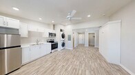 This 430 square foot studio apartment in Bend, Oregon offers a thoughtfully designed living space that maximizes functionality. The open-concept floor plan combines the kitchen, living room, and sleeping area, creating a sense of spaciousness. The kitchen is equipped with modern stainless steel appliances, including a full-size refrigerator, stove, and microwave, as well as ample white cabinetry for storage. A standout feature is the in-unit laundry, with a stacked washer and dryer conveniently located in the kitchen area. The living space is enhanced by a sleek fireplace, adding both warmth and ambiance. Large windows allow natural light to flood the space, while offering views of the surrounding landscape. The bathroom features a clean, white design with a vanity and standard fixtures. Throughout the apartment, light-toned wood-look flooring unifies the space and complements the neutral wall color. Two closets provide generous storage options, including a large Murphy bed cabinet that can be used to conceal the bed when not in use, further maximizing the living area. Recessed lighting throughout ensures even illumination. This efficient studio combines modern amenities with smart design, perfect for those seeking a compact yet comfortable living space.