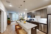 This well-designed 1-bedroom, 1-bathroom residence offers a thoughtfully organized single-floor layout that maximizes every square foot. The open-concept living and kitchen area serves as the heart of the home, where a large granite-topped island with seating anchors the space. The kitchen is outfitted with dark espresso cabinetry, a white tile backsplash, and a full suite of stainless steel appliances including a refrigerator, range, microwave, and dishwasher. Stylish pendant lights hang above the island, adding a contemporary accent. Light hardwood flooring flows throughout, complementing the neutral color palette.

The living room benefits from a large window that invites abundant natural light, with a ceiling fan overhead contributing to a comfortable atmosphere. The generously sized primary bedroom also features a ceiling fan and a large window, creating a bright and airy retreat, with easy access to a closet and the bathroom. The bathroom includes a granite-topped vanity with dark cabinetry and a large mirror, and is paired with an in-unit stacked washer and dryer for added convenience. Clean lines, modern finishes, and a cohesive design aesthetic define this efficient and stylish residence.