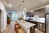 This well-designed 1-bedroom, 1-bathroom residence offers a thoughtfully organized single-floor layout that maximizes every square foot. The open-concept living and kitchen area serves as the heart of the home, where a large granite-topped island with seating anchors the space. The kitchen is outfitted with dark espresso cabinetry, a white tile backsplash, and a full suite of stainless steel appliances including a refrigerator, range, microwave, and dishwasher. Stylish pendant lights hang above the island, adding a contemporary accent. Light hardwood flooring flows throughout, complementing the neutral color palette.

The living room benefits from a large window that invites abundant natural light, with a ceiling fan overhead contributing to a comfortable atmosphere. The generously sized primary bedroom also features a ceiling fan and a large window, creating a bright and airy retreat, with easy access to a closet and the bathroom. The bathroom includes a granite-topped vanity with dark cabinetry and a large mirror, and is paired with an in-unit stacked washer and dryer for added convenience. Clean lines, modern finishes, and a cohesive design aesthetic define this efficient and stylish residence.