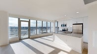This well-appointed 2-bedroom, 2-bathroom unit offers a thoughtfully designed open-concept layout bathed in natural light. The combined kitchen and living area serves as the heart of the home, anchored by expansive floor-to-ceiling windows and sliding glass doors that frame sweeping panoramic city views and lead to an outdoor balcony. Light wood-tone flooring runs throughout, complementing the bright white walls and clean-lined aesthetic.

The kitchen is outfitted with stainless steel appliances — including a range, microwave, and refrigerator — white upper cabinetry, sleek lower cabinets, a white subway tile backsplash, and granite countertops that extend to a functional kitchen island with an undermount sink.

Both bedrooms are generously sized, filled with natural light from large windows overlooking the cityscape, and finished with the same light hardwood flooring. Each room offers a calm, neutral palette ideal for a variety of layouts. The two bathrooms feature granite-topped vanities with dark cabinetry, tiled walk-in showers, and clean, modern fixtures. Two closets provide practical storage, with built-in shelving and hanging rods. A hallway connects the spaces, and the entry features a smart lock panel for added convenience.