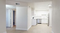 Located at 7007 W Indian School in Phoenix, Arizona, this single-floor unit offers a thoughtfully updated interior with a bright, neutral color palette and light wood-style flooring that flows consistently throughout the space. The kitchen serves as a standout feature, equipped with crisp white shaker-style cabinetry, white subway tile backsplash, light countertops, and a full suite of stainless steel appliances including a range, dishwasher, refrigerator, and microwave. Overhead fluorescent lighting keeps the kitchen well-lit and functional. The layout includes multiple living and sleeping areas, each finished with the same wood-style flooring and warm beige tones on the walls. Several rooms benefit from windows fitted with horizontal blinds, allowing natural light to filter in while maintaining privacy. Textured ceilings are present throughout, adding a tactile contrast to the otherwise smooth wall surfaces. The bathroom is clean and simply appointed, featuring a full tub-shower combination, toilet, and matching light flooring. The overall design emphasizes a clean, move-in-ready aesthetic with modern updates that provide a comfortable and functional living environment.