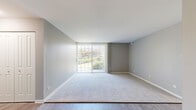 Located at 4773 Lake Valley Dr in Lisle, Illinois, this single-floor residence offers a clean, modern aesthetic defined by neutral gray walls, white trim, and a thoughtful mix of plush carpeting and wood-look luxury vinyl flooring throughout. The spacious living area is a standout feature, anchored by a full-width sliding glass door dressed with vertical blinds that floods the room with natural light and opens to views of lush greenery outdoors. The living space transitions seamlessly into additional areas via a central hallway with louvered closet doors, providing ample storage. The updated kitchen is well-appointed with crisp white cabinetry, granite-style countertops, a gray subway tile backsplash, stainless steel refrigerator, and a dishwasher — all set on wood-look flooring for easy maintenance. The bedrooms are carpeted and generously proportioned, with windows that invite natural light. One bedroom features a ceiling fan with a brushed gold fixture, adding a functional and stylish touch. The hallway connecting the rooms is bright and efficiently laid out, reflecting a practical and comfortable floor plan overall. This residence combines updated finishes with a neutral palette, creating a versatile and move-in-ready living environment.