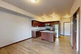 Located at 104 S Olympic Ave in Arlington, WA, this one-bedroom, one-bathroom unit offers a well-designed, single-floor layout that maximizes every square foot of its compact footprint. The open-concept main living area seamlessly connects the kitchen, dining, and living spaces, creating a bright and functional hub for daily living. The kitchen is a standout feature, showcasing rich dark-wood cabinetry, granite countertops, a central island with additional storage, and a full suite of stainless steel appliances including a refrigerator, range, microwave, and dishwasher. Light wood-tone flooring flows throughout the main living areas, contributing to a warm, cohesive aesthetic. A hallway leads from the main living area to the bedroom, which features plush carpeting, a window with views of the surrounding greenery, and a spacious closet with wire shelving for organized storage. A second closet provides additional storage convenience. The full bathroom is finished with matching dark-wood cabinetry, granite countertops, a tub/shower combination, and wood-tone flooring that ties into the rest of the unit's design. Neutral wall tones and consistent trim work throughout lend the space a clean, move-in-ready appeal.