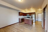 Located at 104 S Olympic Ave in Arlington, WA, this one-bedroom, one-bathroom unit offers a well-designed, single-floor layout that maximizes every square foot of its compact footprint. The open-concept main living area seamlessly connects the kitchen, dining, and living spaces, creating a bright and functional hub for daily living. The kitchen is a standout feature, showcasing rich dark-wood cabinetry, granite countertops, a central island with additional storage, and a full suite of stainless steel appliances including a refrigerator, range, microwave, and dishwasher. Light wood-tone flooring flows throughout the main living areas, contributing to a warm, cohesive aesthetic. A hallway leads from the main living area to the bedroom, which features plush carpeting, a window with views of the surrounding greenery, and a spacious closet with wire shelving for organized storage. A second closet provides additional storage convenience. The full bathroom is finished with matching dark-wood cabinetry, granite countertops, a tub/shower combination, and wood-tone flooring that ties into the rest of the unit's design. Neutral wall tones and consistent trim work throughout lend the space a clean, move-in-ready appeal.