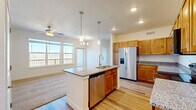 Located in Johnstown, Colorado, this well-appointed one-bedroom, one-bathroom residence offers a thoughtfully designed open-concept floor plan. The kitchen serves as the centerpiece of the living space, featuring a large central island with a double-basin sink, granite countertops, and warm knotty alder cabinetry that extends to the upper walls for generous storage. Stainless steel appliances — including a French door refrigerator with ice maker, electric range, built-in microwave, and dishwasher — complete the kitchen. Pendant lighting above the island and recessed ceiling lights illuminate the space, while durable hardwood-style flooring flows throughout the kitchen and main areas. The open living area, finished with plush carpet, is brightened by large windows that frame expansive views of the surrounding Colorado landscape and allow abundant natural light. A ceiling fan adds comfort to both the living area and bedroom. The bedroom is a comfortable retreat with carpet flooring, a ceiling fan, a dedicated closet, and a wide window showcasing the open plains beyond. The full bathroom includes a vanity with granite countertop, a tub/shower combination, and hardwood-style flooring, maintaining a consistent and clean aesthetic throughout the home.