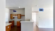 This single-story home offers a practical and functional layout across a well-organized floor plan. The living area welcomes residents with rich hardwood-style flooring, a ceiling fan with light fixture, and generous natural light streaming through a large window and an exterior door fitted with blinds, providing easy access to the outdoors.

The kitchen is designed for efficiency, featuring warm wood cabinetry, light countertops, a peninsula breakfast bar that opens to the main living space, a dishwasher, and a double-basin sink. A range hood is installed above the cooktop area, and overhead lighting ensures a well-lit workspace.

The bedrooms are carpeted for comfort, each equipped with a ceiling fan and windows with blinds that allow natural light while maintaining privacy. The rooms offer ample wall space suitable for a variety of furniture arrangements.

Two full bathrooms serve the home. One features tile walls, a single-sink vanity with wood cabinetry, a mirror, and a shower-tub combination. The second bathroom includes a wider vanity with an integrated sink, wood cabinetry, grab bars for accessibility, a tub, and tile accent details.

Throughout the home, neutral wall tones, clean white trim, and consistent flooring materials create a cohesive and move-in ready environment.