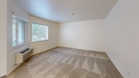 Located in Vancouver, Washington, this thoughtfully designed one-bedroom, one-bathroom residence offers a functional and comfortable single-floor layout. The open kitchen and living area serves as the heart of the home, featuring wood-look flooring, white cabinetry with warm wood trim accents, grey countertops, and a full suite of stainless steel appliances including a refrigerator, electric range with overhead microwave, and dishwasher. A peninsula counter provides additional workspace and helps define the transition between the kitchen and living area. A dedicated in-unit laundry area with a stacked washer and dryer is conveniently accessible from the kitchen corridor. The bedroom is generously sized, finished with plush wall-to-wall carpeting, and benefits from natural light through windows with views of surrounding greenery. It connects directly to a walk-in closet outfitted with wood shelving and hanging rods, offering ample storage. The full bathroom features a wide vanity with grey countertops, a large mirror, wood-look flooring, and a tub-shower combination. Neutral tones and clean finishes throughout lend the space a bright, move-in-ready appeal.