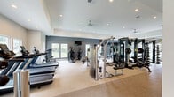 Located at 240 Ivy Meadow Ln in Durham, NC, this generously sized fitness center offers a comprehensive, well-appointed exercise facility spread across a single floor. The space is thoughtfully organized into distinct workout zones, each designed to support a wide range of fitness activities.

The cardio area is equipped with multiple treadmills, elliptical trainers, and stair climbers, all positioned to take advantage of the natural light streaming in through large windows. Ceiling fans overhead ensure consistent airflow throughout the space. The strength training section features a robust selection of cable machines, multi-functional power racks, a full dumbbell rack, weight benches, and a heavy punching bag, catering to both functional and traditional training styles.

A dedicated open floor area accommodates flexibility and accessory training, complete with stability balls and additional equipment. Motivational wall decals add an energetic atmosphere to the space.

Adjacent to the main exercise floor, a comfortable lounge area provides a welcoming retreat, furnished with a pool table, plush seating, and large windows that offer views of the surrounding greenery. Recessed lighting and tasteful wall art complete the refined aesthetic.

Throughout the facility, neutral tones, tray ceilings, and an open layout create a bright, clean, and inviting environment well-suited for an active lifestyle.