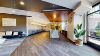 Located at 360 N First St in Minneapolis, Minnesota, this well-appointed amenity space spans a generous single floor and is designed to serve as a dynamic communal hub. The main lounge area makes an immediate impression with its warm wood-paneled ceiling, wide-plank hardwood flooring, and an eye-catching marble-topped island that serves as a central focal point. Pendant lighting fixtures and recessed lighting create a welcoming ambiance throughout, while large windows allow natural light to pour in and offer views of the surrounding neighborhood.

A glass-enclosed private meeting or conference room features a round wood table, mid-century modern upholstered chairs, a striking copper pendant light, and textured geometric wallcovering. Floor-to-ceiling windows provide an abundance of natural light and outdoor views, making it an ideal setting for focused gatherings.

The screening and game room offers tiered rows of plush, oversized sofas oriented toward a large wall-mounted flat-screen TV with flanking sconce lighting. A billiards table is also present, adding a recreational dimension to the space.

Extending the living area outdoors, a spacious terrace features durable patio seating arrangements and open railings that frame views of the lush, tree-lined surroundings — perfect for relaxing or socializing al fresco.