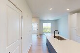 Located at 65 Middle River Rd in Chattanooga, TN, this thoughtfully designed one-bedroom, one-bathroom unit offers a clean, contemporary aesthetic throughout. Light-toned hardwood flooring flows seamlessly across the entire space, complemented by crisp white walls and recessed lighting that create a bright, airy atmosphere.

The open-concept kitchen and dining area serves as the heart of the unit, anchored by a navy blue center island with a white quartz countertop, undermount sink, and matte black faucet. White shaker-style cabinetry with gold hardware lines the walls, accompanied by a full suite of stainless steel appliances including a refrigerator, range, and microwave. A white subway tile backsplash adds a clean, modern touch.

The living area opens directly to a private balcony through full-height sliding glass doors, allowing natural light to pour in and offering views of the surrounding Chattanooga neighborhood. The bedroom is a well-proportioned, serene retreat with direct access to the bathroom and generous closet space.

The bathroom features a dual-sink vanity with navy blue cabinetry, white quartz countertops, large mirrors with modern lighting, matte black fixtures, and a tiled walk-in shower. A dedicated closet space houses a stacked full-size washer and dryer, adding everyday convenience to this well-appointed unit.