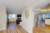 Located at 21495 LeMay Dr in Riverside, CA, this single-story home offers a thoughtfully designed layout across a generous floor plan. The interior is finished with warm hardwood-style flooring throughout the main living areas, complemented by neutral-toned walls that create a bright, welcoming ambiance.

The open-concept living and dining area flows naturally toward sliding glass doors that lead to a private patio, filling the space with natural light. The kitchen is a standout feature, boasting white cabinetry, granite countertops, stainless steel appliances including a refrigerator and dishwasher, a center island, and a distinctive tray ceiling with recessed lighting — all opening seamlessly to the dining area.

The spacious primary bedroom offers plush carpeting and ample closet space, including a well-sized walk-in closet with double hanging rods. The bathrooms are finished with granite vanities and hardwood-style flooring, with the primary bath featuring a walk-in shower. A second comfortable bedroom enjoys natural light from a window with neighborhood views.

Additional highlights include a pantry, utility room, and two garages providing exceptional storage and parking. The exterior features a stucco facade with a red tile roof, mature landscaping, and a grassy yard, rounding out this complete and comfortable Riverside home.
