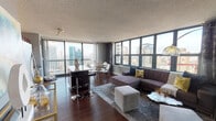Located in Chicago's vibrant River North neighborhood, this high-rise residence at 28 W Superior Street offers an elevated urban living experience defined by sweeping, floor-to-ceiling views of the Chicago skyline. The open-concept living and dining area is anchored by expansive corner windows that flood the space with natural light and frame dramatic cityscape panoramas on multiple sides. Rich hardwood flooring runs throughout, complementing the contemporary design aesthetic.

The kitchen is well-appointed with stainless steel appliances, including a refrigerator, dishwasher, microwave, and range, alongside rich dark wood cabinetry and granite countertops. A central kitchen island with bar seating provides both additional prep space and a natural gathering point that connects seamlessly to the living and dining areas.

The living room is generously sized, accommodating a large sectional sofa oriented to maximize the skyline views, with ample space for additional seating. The primary bedroom features its own window with city views, dark hardwood floors, and a textured accent wall that adds depth and warmth to the room. The bathroom includes a full tub-shower combination with tile surround, a granite-topped vanity, and neutral toned walls, offering a clean, functional design.