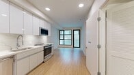 This 430-square-foot, one-bedroom, one-bathroom apartment is located on the second floor at 1641 Lincoln Blvd in Santa Monica, CA. The unit showcases a clean, modern design throughout, with light wood-style flooring and crisp white walls creating a bright, cohesive aesthetic.

The open kitchen flows seamlessly into the living area and features sleek, high-gloss white cabinetry extending to the ceiling, a marble-style quartz backsplash, white countertops, and a full suite of stainless steel appliances including a refrigerator, dishwasher, electric range, and microwave. Recessed lighting illuminates the space efficiently.

The living area benefits from large, black-framed windows and a glass sliding door that invite natural light and provide views of the surrounding building exterior. A ceiling fan adds both function and style.

The 130-square-foot bedroom continues the light wood flooring and features a large black-framed window with roller shade, a ceiling fan with light fixture, and clean white walls offering a calm, restful environment.

The bathroom is finished with elegant large-format hexagonal marble-look tile flooring and full white tile surround in the tub/shower combination, complemented by brushed gold fixtures and towel bars, giving the space a polished, contemporary feel.