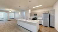Located at 5000 Mountain Springs Dr in Nashville, TN, this two-story home offers a well-designed layout across three bedrooms and two bathrooms. The main level is anchored by a contemporary kitchen featuring a large central island with a white quartz countertop, undermount sink, pendant lighting, gray shaker-style cabinetry, a white subway tile backsplash, and a full suite of stainless steel appliances including a range, microwave, dishwasher, and refrigerator. Light wood-style flooring flows throughout the kitchen and connects seamlessly to the living area. The spacious living room is highlighted by a ceiling fan, recessed lighting, and a charming arched window detail that introduces natural light. Carpeted bedrooms provide a comfortable feel, each equipped with ceiling fans and windows with blinds. The generously sized primary bedroom includes a walk-in closet with built-in wire shelving. Additional closets offer further storage throughout. The bathrooms are finished with gray vanity cabinetry, white quartz countertops, wood-style flooring, and a tiled tub-shower combination. A dedicated laundry room with wire shelving and utility hookups adds everyday convenience. Carpeted staircases with a sleek metal handrail connect the two levels of this functional Nashville home.