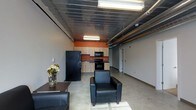 Located at 369 E Gay St in the heart of Columbus, Ohio, this single-floor space blends industrial aesthetics with functional design. The open-plan layout is anchored by a striking exposed ceiling that showcases raw metal decking and visible ductwork, lending the space an authentic urban character. Polished concrete floors run throughout, offering a clean, durable surface that complements the industrial ambiance.

A compact kitchenette is nestled along one wall, featuring warm wood cabinetry set against a bold terracotta-orange accent wall that serves as a focal point. The kitchenette is equipped with full-size appliances including a refrigerator, microwave, and range, making the space well-suited for extended occupancy or employee use. The adjoining open area provides generous room for lounge seating or flexible workspace arrangements, as seen with the leather seating arrangement near the entry.

Fluorescent strip lighting runs parallel to the ductwork overhead, ensuring the space is well-lit throughout. Neutral gray walls keep the environment clean and versatile, allowing the space to adapt to a variety of uses. A secondary room or corridor is accessible toward the rear, offering additional privacy or storage potential. Overall, the space delivers a modern, loft-inspired atmosphere well-positioned in downtown Columbus.