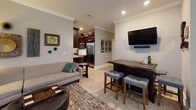 This single-floor residence offers a cohesive and well-organized layout designed for comfortable living. The open-concept living area connects seamlessly to a bar-height dining counter and flows into the kitchen, which features a galley-style configuration with rich dark cabinetry, granite countertops, a stone tile backsplash, and stainless steel appliances. Crown molding and recessed lighting add a polished finish to the shared living space.

The dining room accommodates a round table and benefits from multiple windows fitted with horizontal blinds, allowing natural light to fill the room. A flexible secondary room with carpeted flooring and a large window serves well as a sitting room, office, or guest space.

The primary bedroom is distinguished by an elegant tray ceiling with crown molding detail and soft carpeted flooring. It provides ample space for a full furniture suite and is complemented by a private bathroom featuring a dark wood vanity with granite countertops and a shower.

A second full bathroom mirrors the same design aesthetic, with granite countertops, a dark wood vanity, a large mirror, and a shower-tub combination. Throughout the residence, warm neutral wall tones, light wood-style flooring in common areas, and consistent trim work create a unified and inviting atmosphere.
