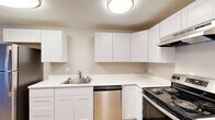Located at 401 E Magnesium Rd in Spokane, WA, this thoughtfully updated 2-bedroom, 1-bathroom unit offers a functional single-floor layout with modern finishes throughout. The combined kitchen and living area forms the heart of the home, where the kitchen impresses with crisp white shaker-style cabinetry, bright white quartz-style countertops, stainless steel appliances including a dishwasher and electric range, and a single-basin sink. The living room features warm luxury vinyl plank flooring that carries throughout the unit, a textured ceiling, and a sliding glass door that fills the space with natural light and provides direct outdoor access. Both bedrooms are comfortably proportioned with neutral gray walls, LVP flooring, windows with blinds, and baseboard heating. The primary bedroom includes a dedicated closet with sliding panel doors. The bathroom is clean and functional, featuring a full tub-shower combo with built-in shelving, a white vanity, and matching fixtures. Additional spaces include a utility room and a dedicated closet, providing practical storage solutions. The unit presents a cohesive, move-in-ready aesthetic with updated interiors throughout.