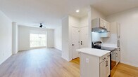 Located at 104 E 28th Terrace in Kansas City, MO, this well-designed one-bedroom, one-bathroom residence offers a clean, modern aesthetic throughout. The open-concept kitchen and living area forms the heart of the home, featuring light hardwood-style flooring, crisp white walls, and crown molding that add a refined touch. The kitchen is outfitted with white shaker-style cabinetry, black hardware accents, a white quartz peninsula countertop, subway tile backsplash, and a full suite of stainless steel appliances including an electric range, dishwasher, and refrigerator. A ceiling fan overhead and large windows allowing generous natural light define the living room, which flows seamlessly from the kitchen. The spacious bedroom is carpeted for comfort, features its own ceiling fan, and is brightened by a large window with outdoor views of surrounding greenery. A dedicated closet provides ample storage. The bathroom showcases a clean, contemporary design with a white tile floor accented by a classic diamond pattern, a white vanity with black-framed mirror, black fixtures, and a tub-shower combination. This residence combines functional design with modern finishes throughout.