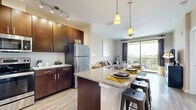 This thoughtfully designed 1-bedroom, 1-bathroom residence offers a efficient and functional single-floor layout. The open-concept kitchen and living area form the heart of the unit, anchored by a stunning granite-topped island with bar seating and an undermount sink, ideal for casual dining or entertaining. Rich dark-wood cabinetry, stainless steel appliances, subway tile backsplash, and track lighting lend a polished, contemporary feel to the kitchen. Light wood-style flooring extends throughout the main living area, enhancing the bright, airy atmosphere.

The living room is generously proportioned with a ceiling fan, neutral toned walls, and large floor-to-ceiling sliding glass doors that open onto a private balcony, filling the space with natural light and offering open outdoor views of surrounding greenery. The balcony provides additional space for outdoor seating.

The bedroom is a comfortable retreat featuring plush carpeting, large windows with scenic views, a ceiling fan, and ample natural light. The bathroom connects conveniently to the bedroom and hallway, featuring granite countertops, dark cabinetry, and clean tile flooring. Together, these rooms create a cohesive, modern living space that balances style and practicality.