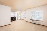 This single-floor residential unit offers a thoughtfully designed layout that balances open living spaces with practical functionality. The spacious living area is carpeted and bathed in natural light from large windows fitted with blinds, providing views of the surrounding neighborhood. A wall-mounted HVAC unit ensures year-round climate control, and a sliding glass door leads to a private balcony, extending the living space outdoors.

The kitchen is a standout feature, boasting a modern design with two-tone cabinetry — dark lower cabinets paired with crisp white upper cabinets — set against light countertops. A full suite of stainless steel appliances, including a refrigerator, electric range, microwave, and dishwasher, is complemented by track lighting and durable hardwood-style flooring.

The bedrooms are generously sized, each carpeted and filled with natural light. One bedroom includes a walk-in closet with wire shelving, offering ample storage. The unit includes two bathrooms: one with a sliding glass shower/tub enclosure and hardwood-style flooring, and another with grab bars, a standard toilet, and light countertops. Warm wood-toned interior doors and rich baseboards throughout tie the space together with a cohesive, residential feel.