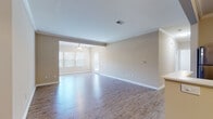 This single-story residence offers a thoughtfully designed open layout that connects the main living spaces with ease. The expansive living and dining areas are finished with durable wood-look flooring that runs throughout the main spaces, complemented by crisp white crown molding and neutral-toned walls that create a clean, welcoming atmosphere. A ceiling fan serves the living area, while multiple windows fitted with blinds allow natural light to filter through comfortably.

The kitchen is well-equipped, featuring warm honey-toned cabinetry, light granite-style countertops, and a full suite of stainless steel appliances including a range, microwave, refrigerator, and sink. A peninsula provides additional counter space and separates the kitchen from the adjacent dining area, which is accented by a small chandelier.

The bedrooms are carpeted for comfort and maintain the same neutral palette found throughout the home. Two full bathrooms each include wood-toned vanities with granite-style countertops, a tub-shower combination, and tile-look flooring. A dedicated laundry area accommodates a full-sized washer and dryer with overhead shelving for added storage.