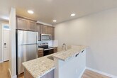 This two-story home in Twin Falls, Idaho offers a practical and modern layout spread across two floors. The main level features an inviting entrance that leads into a bright living room with wood-style flooring, and a well-equipped kitchen highlighted by rich dark wood cabinetry, granite countertops, stainless steel appliances, and a peninsula with bar seating — ideal for casual dining. A convenient half bathroom is also located on this floor. The main level is completed by a dedicated laundry area and access to a private patio, perfect for outdoor relaxation. Upstairs, two generously sized bedrooms are carpeted for comfort and filled with natural light through window treatments. The primary bedroom is a spacious retreat with its own closet. A hallway connects the upper-level spaces, which include two full bathrooms featuring clean white tub surrounds and granite-topped vanities with dark wood cabinetry consistent with the home's overall aesthetic. Three closets provide ample storage throughout. Neutral warm-toned walls, recessed lighting, and wood-style flooring on the main level create a cohesive, clean ambiance that flows seamlessly from room to room.